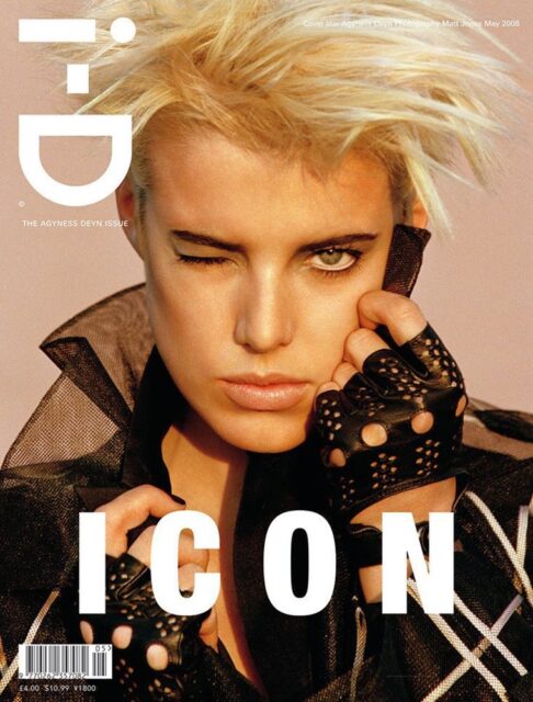 A blonde model with short, spiky hair winks at the camera while wearing a black outfit with lace gloves on the cover of i-D magazine. The word "ICON" is prominently displayed across the bottom.