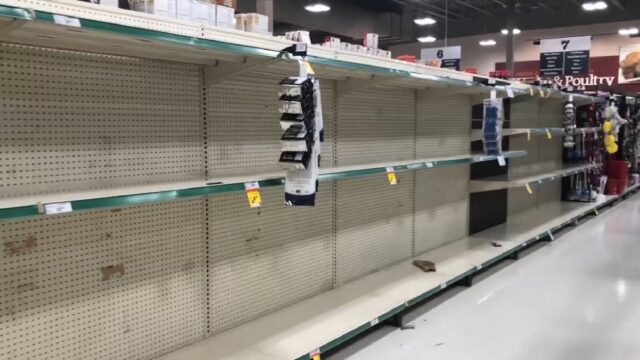 Empty store shelves in a grocery store during a period of panic buying, showcasing the impact of people hoarding essential items.