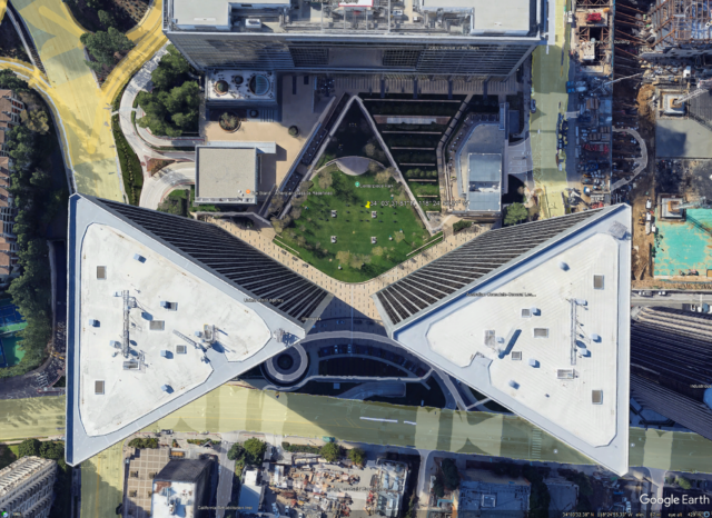 An aerial view of the Century Plaza Towers in Century City, Los Angeles, California, USA, showing two triangular skyscrapers and the green space between them, known as Centerpiece Park.