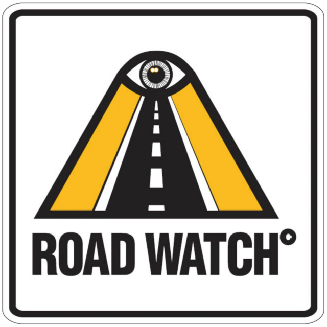 A sign for "Road Watch," featuring a stylized road that leads to an eye at the top. The eye symbolizes surveillance, and the sign is likely used in areas where the Community Road Watch program is active, indicating that traffic is being monitored by the community.