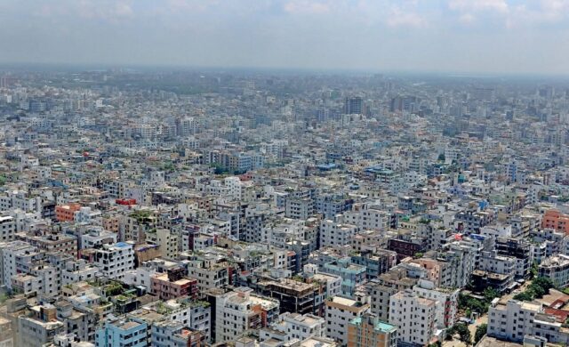 - Aerial view of Dhaka in Bangladesh, showing a densely packed urban landscape with numerous buildings tightly clustered together. The city stretches into the horizon, illustrating the high population density and extensive development characteristic of the area.