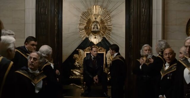 A secretive meeting in a lavish room with a golden throne and a radiant sunburst pattern on the wall. The room is filled with men in formal, ceremonial attire, symbolizing a secret society or organization.