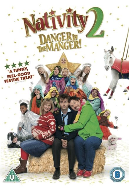 The movie poster for "Nativity 2: Danger in the Manger!" features a joyful group of children dressed in nativity-themed costumes, forming a pyramid-like shape with a child dressed as a star at the top. In the foreground, the main characters, including David Tennant, are seated on a hay bale, surrounded by smiling children and a white donkey in a festive outfit. The background is filled with golden stars, creating a festive atmosphere.