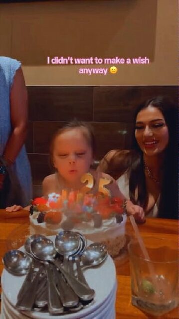 A young girl blows out the candles on a birthday cake with the number "25" on it while sitting on her aunt's lap. The aunt gives a fake smile as the child takes the spotlight. A caption above reads, "I didn't want to make a wish anyway."