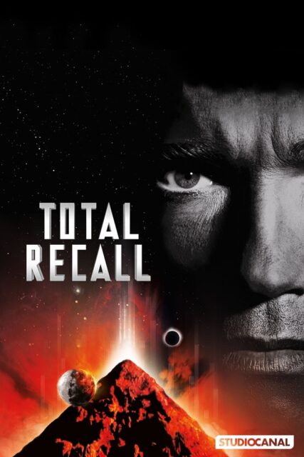 A poster for the movie "Total Recall" featuring the right half of a man's face in grayscale, with only his intense right eye visible. Below, a volcanic, pyramid-like structure erupts against a fiery red-orange background. A planet and an eclipse are visible in the sky above the pyramid-like structure, with the movie title "Total Recall" in bold metallic letters to the left.