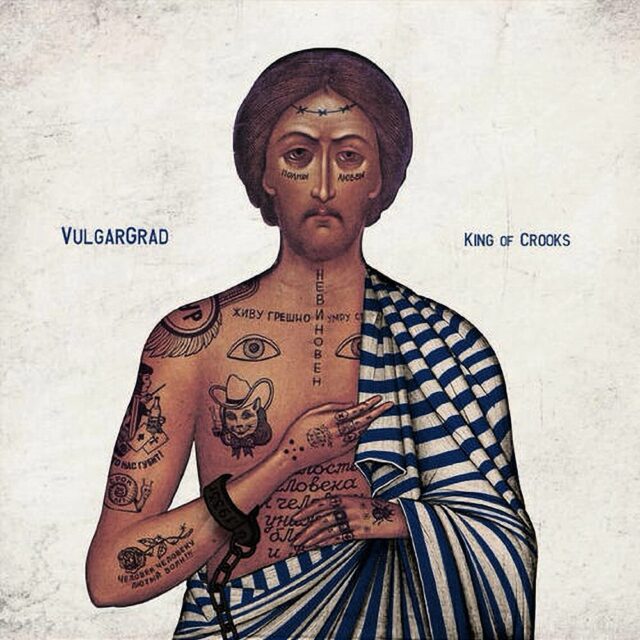 Music album cover for "King of Crooks" by Vulgargrad featuring a stylized depiction of Jesus Christ in the style of an Orthodox icon. The figure is covered in various tattoos, including phrases and symbols, and wears a striped robe. The text "Vulgargrad" appears on the left side and "King of Crooks" on the right.