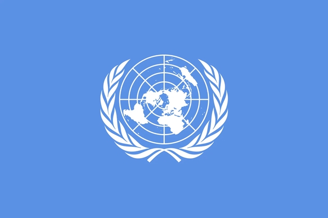 The flag of the United Nations featuring a world map centered on the North Pole, overlaid with a grid representing latitude and longitude, surrounded by two symmetrical olive branches, on a light blue background.